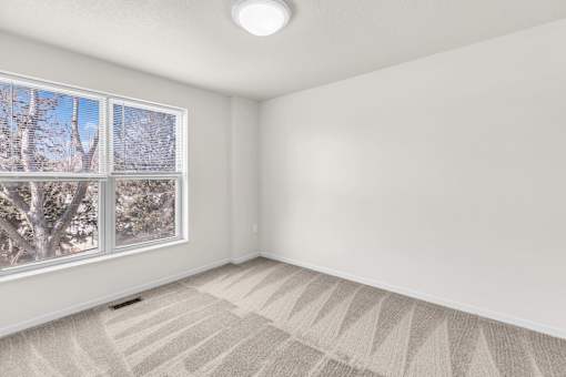 A room with a large window and a carpeted floor.