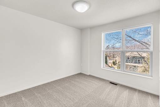 A room with a window showing a view of a house and trees.