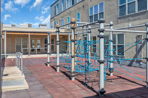 A playground with a blue climbing structure on a brick patio.