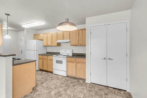 A kitchen with white appliances and wooden cabinets.