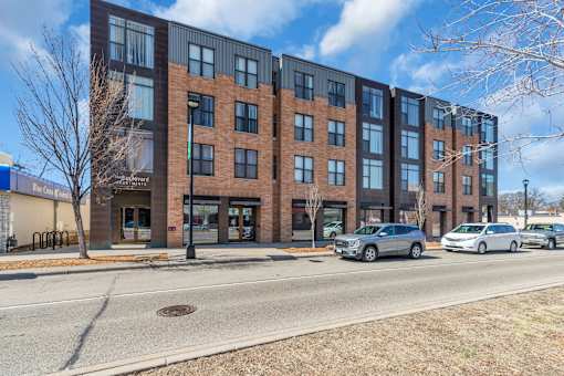 A modern brick building with a parking lot in front.