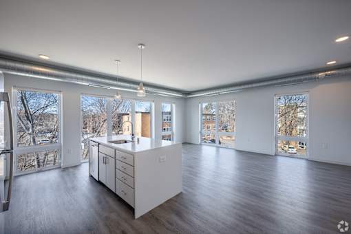 A large, empty room with a kitchen island in the middle.