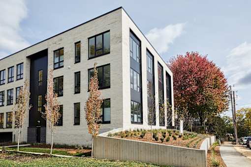 A modern building with a grey facade and black windows.