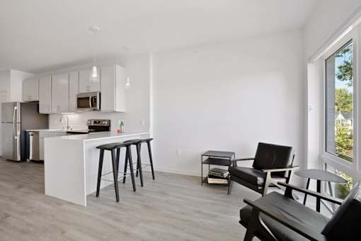 A kitchen with white cabinets and a white island with bar stools.