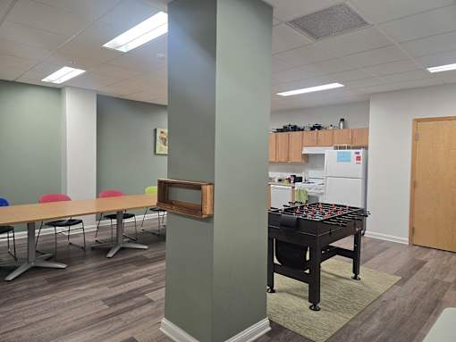 A room with a table, chairs, and a foosball table.