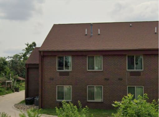 A red brick house with a brown roof and a driveway.
