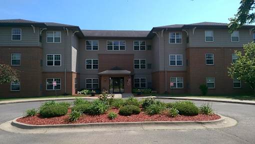 A large apartment complex with a red brick facade and a landscaped front area.