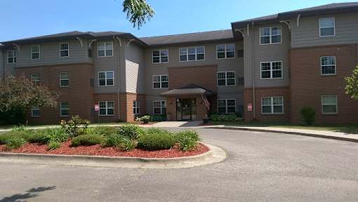 A large apartment complex with a red brick facade and a landscaped front yard.