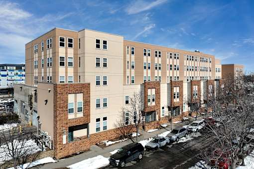 A large apartment building with a parking lot in front.