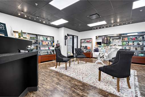 A black chair sits in the middle of a room with a wooden floor and a white rug.