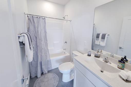 A white bathroom with a toilet, sink, and shower.