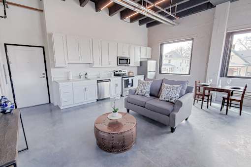 A modern kitchen with white cabinets and a grey couch.