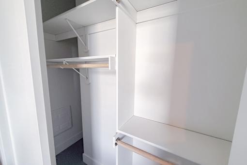 Walk-in closet with multiple shelves and hanging bars.