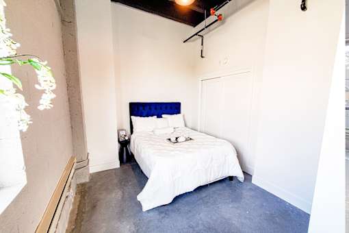 A bed with a blue headboard sits in a room with white walls.