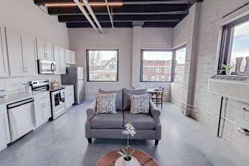 Open concept floor plan with large windows and white kitchen cabinets.