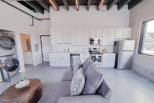 Open concept floor plan featuring white kitchen cabinets and stainless steel appliances.