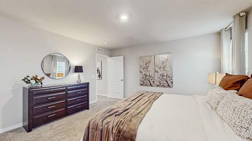 A bedroom with a large bed and a dresser with a mirror.