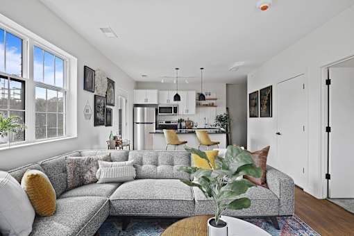 A grey couch with a yellow pillow is in the middle of a living room.