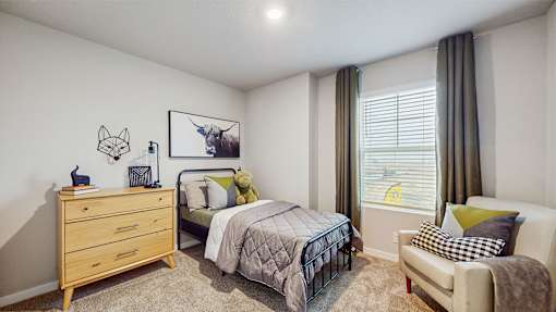 A bedroom with a bed, a couch, a dresser, and a window with curtains.