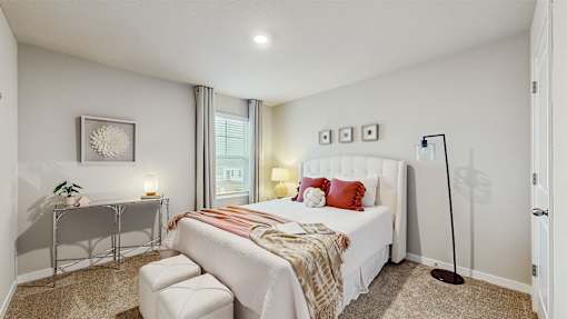 A bedroom with a bed, a chair, and a nightstand.