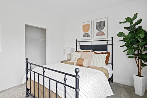 A bedroom with a black metal bed frame and a potted plant on the side table.