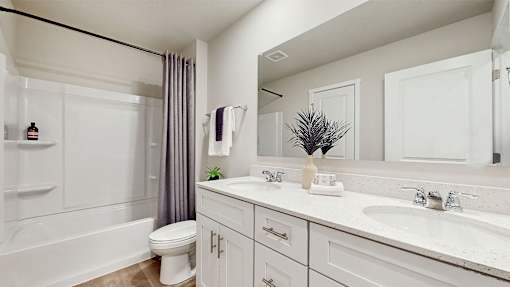 A white bathroom with a toilet, sink, and mirror.