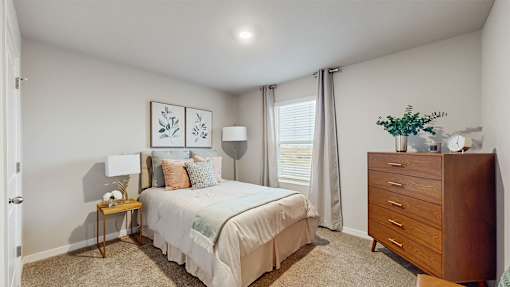 A bedroom with a bed, nightstand, and a carpet.