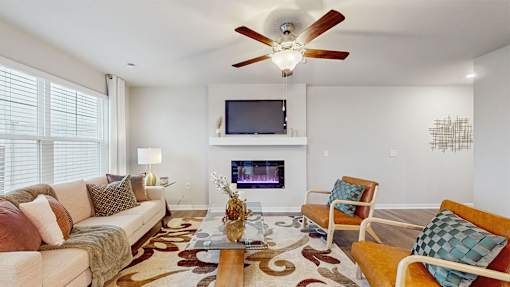 A living room with a couch, chairs, a television, and a fireplace.