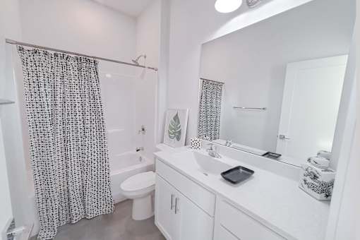 A white bathroom with a shower curtain and a white toilet.