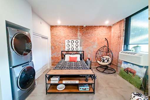 A bedroom with a brick wall and a bed with a black and white comforter.