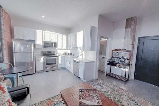 A kitchen with white cabinets and a black fridge.