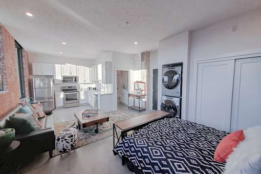 A bedroom with a black and white patterned bedspread and a red pillow.