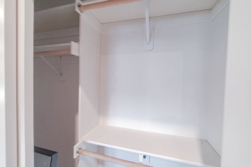 A white closet with a shelf and a white door.