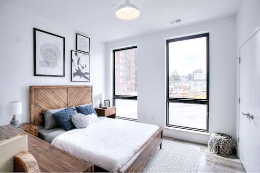 A bedroom with a large bed and a window overlooking a cityscape.
