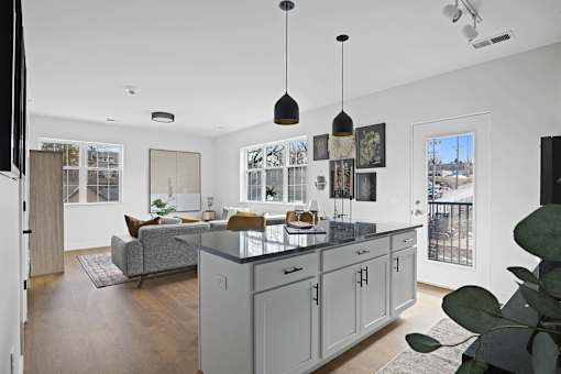 A modern kitchen with a grey island and pendant lights.