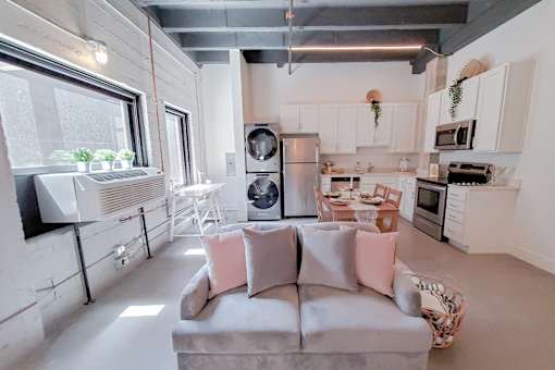 A modern kitchen with a grey couch and a window.