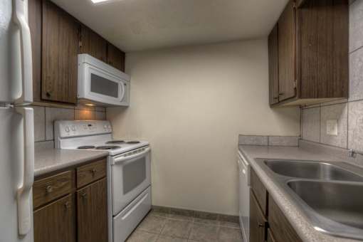 A kitchen with a white refrigerator, white stove, and a white microwave.