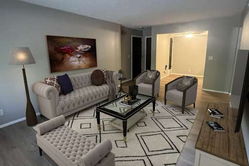A living room with a white couch, a coffee table, and a painting on the wall.