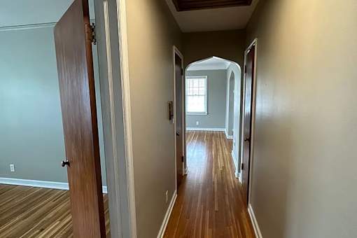 A long hallway with a door on the left and a window on the right.
