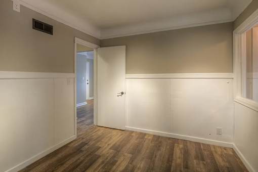 A room with wooden flooring and white walls.