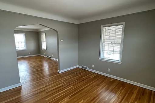 A room with wooden floors and a window with blinds.