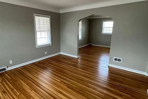 A room with wooden floors and two windows.