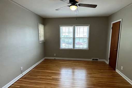 A room with a ceiling fan and wooden flooring.