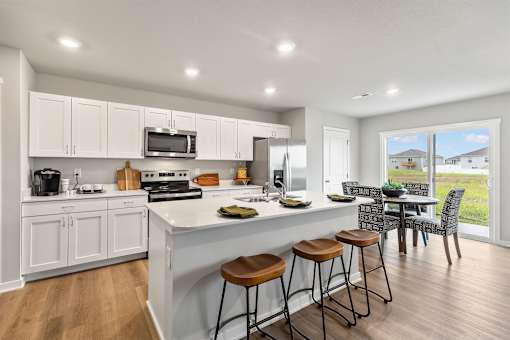 A modern kitchen with white cabinets and a large island with three stools.