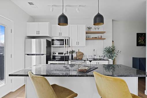 A modern kitchen with a black granite countertop and yellow chairs.