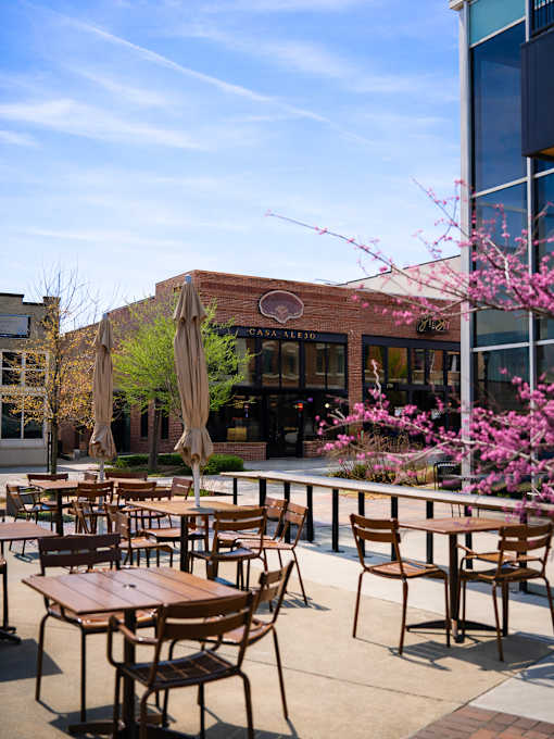 A restaurant with tables and chairs outside with a blue sky in the background.