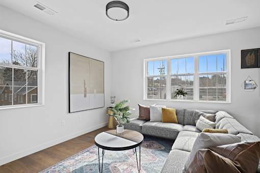 A living room with a grey couch, a small table, and a large window.
