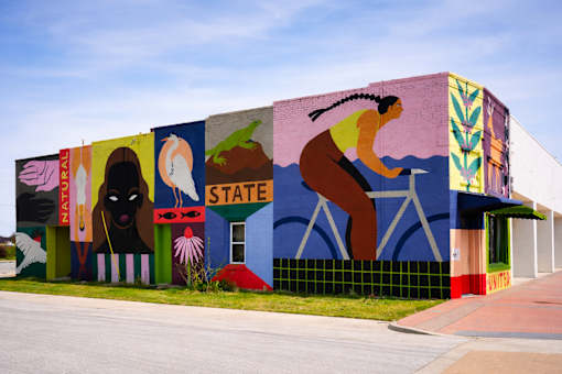 A mural on a building with a person riding a bicycle on it.