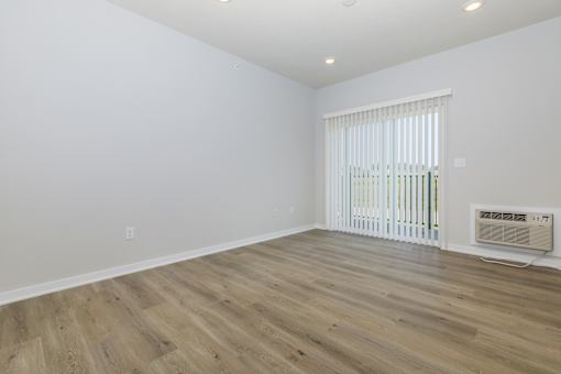 A room with wooden flooring and a window with blinds.