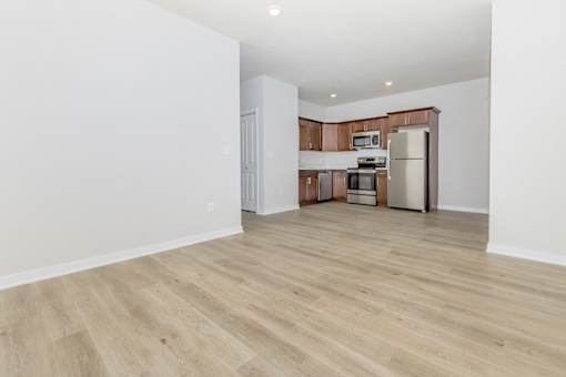 A kitchen with a refrigerator, microwave, and oven is in the background.